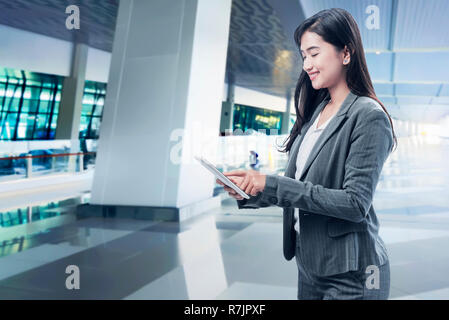 Lächelnd Asian Business Frau mit digitalen Tablette am Flughafen Stockfoto