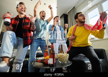 Neugierige junge Männer Sport Wettbewerb zu Hause, glückliche Fans siegreich Schreien Stockfoto