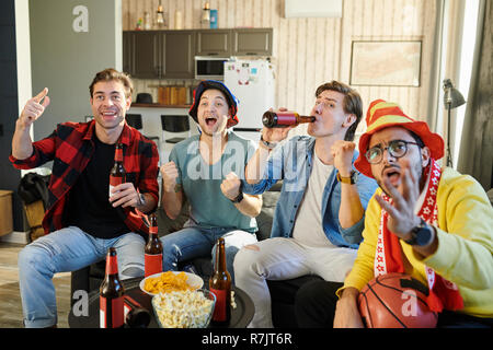 Gruppe junger Männer gemeinsam Fußballspiel im Fernsehen und trinken Bier mit Chips zu Hause Stockfoto
