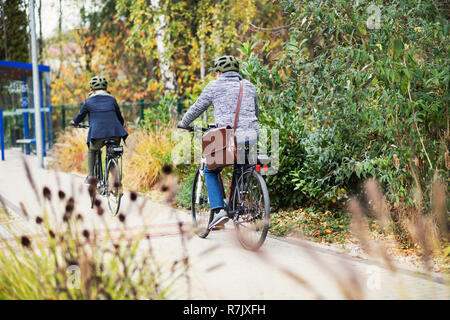 Eine Ansicht der Rückseite des Active Senior Paar mit elektrobikes Radfahren im Freien auf der Weg in die Stadt. Stockfoto