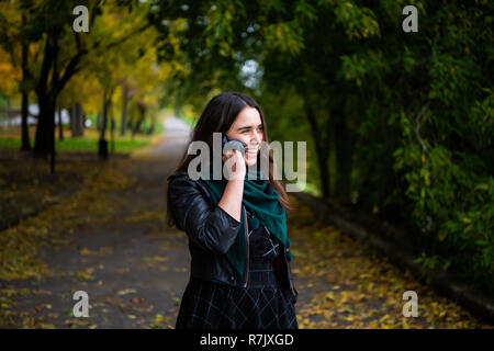 Glückliche junge Frau in ein Gespräch mit einem Smartphone auf einen Anruf. Stockfoto