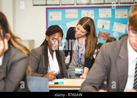 Weiß Lehrer helfen einem Schwarzen ethnischen Minderheit Schülerin in einer britischen British School Stockfoto