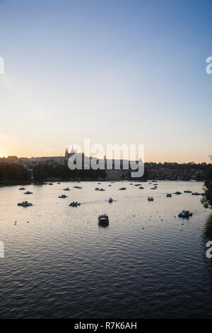 Die Prager Burg und die Boote auf dem Fluss Vltava bei Sonnenuntergang Stockfoto