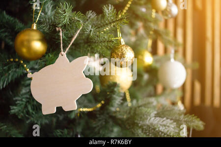 Schwein Spielzeug der Weihnachtsbaum. Goldene Kugeln, Perlen, andere Dekorationen. Neues Jahr symbol Konzept. Sonne orange getönt. Stockfoto