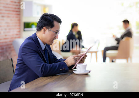 Portrait von Geschäftsmann in Cafe mit smart phone Tablet mit Business Team im Hintergrund arbeiten für coporate Hintergrund arbeiten Stockfoto
