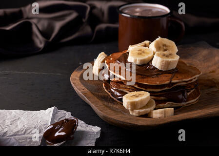 Pfannkuchen mit Banane und Schokolade auf Holzplatte Stockfoto
