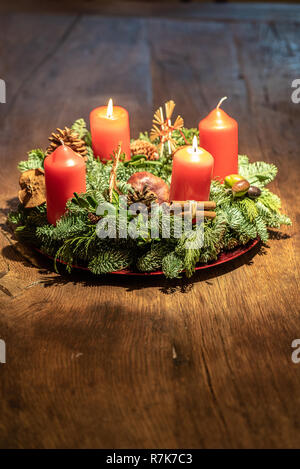 Adventskranz und zwei brennende rote Kerzen an einem hölzernen Tisch Studio Stockfoto