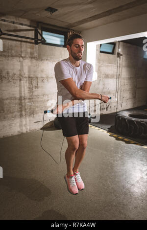 Junger Mann Trainieren mit Springseil in der Turnhalle. Stockfoto