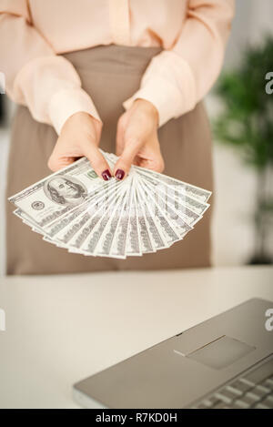 Nicht erkennbare Geschäftsfrau in der ausgestreckten Hände halten Dollar Banknoten. Konzentrieren Sie sich auf das Geld. Stockfoto