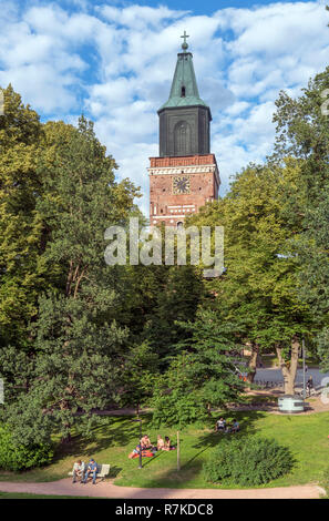 Junge Leute sitzen in Tuomiokirkonpuisto (Kathedrale Park) in der Abendsonne mit der Kathedrale von Turku (Turun tuomiokirkko) hinter, Turku, Finnland Stockfoto