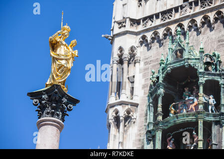 Statue von St. Maria auf eine Spalte in der Mitte des zentralen Platzes Marienplatz in München. Auf der rechten Seite das berühmte Glockenspiel im Turm des Cit Stockfoto