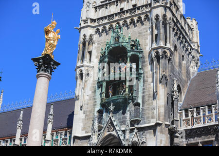 Statue von St. Maria auf eine Spalte in der Mitte des zentralen Platzes Marienplatz in München. Auf der rechten Seite das berühmte Glockenspiel im Turm des Cit Stockfoto