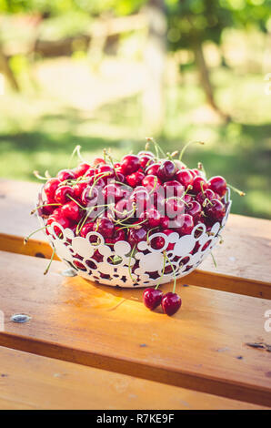 Reife rote Kirsche Obst im Korb auf hölzernen Tisch im Freien Stockfoto