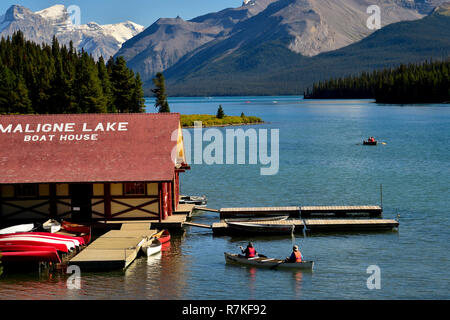 Ein horizontales Landschaftsbild des Bootshauses in Maligne see mit den felsigen Bergen und Menschen Bootfahren auf der see im Jasper National Park Alberta Stockfoto