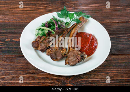 Gebratenes Lamm Rippen auf einem Teller. Appetitanregende Teller auf den hölzernen braun Tabelle Stockfoto