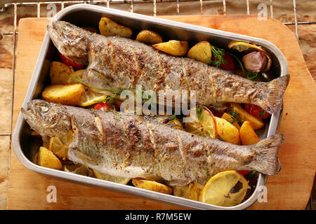 Gebackener Fisch mit Bratkartoffeln in Metallschale Stockfoto