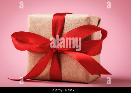 Geschenk mit roter Schleife auf rosa Hintergrund schließen Gebundene Stockfoto