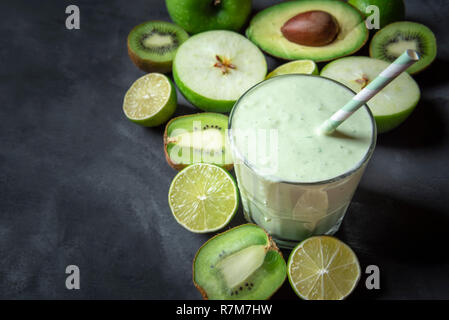 Glas mit einem frischen Smoothie, von grünen Früchten umgeben, auf einem Küchentisch. Kopieren Sie Platz auf der linken Seite. Diät essen. Das gesunde Essen. Vegetarische Mahlzeit. Stockfoto