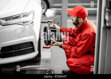 Stattliche Automechaniker in Rot einheitliche Festsetzung Festplatte für Spur am Auto Service Stockfoto