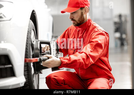 Stattliche Automechaniker in Rot einheitliche Festsetzung Festplatte für Spur am Auto Service Stockfoto