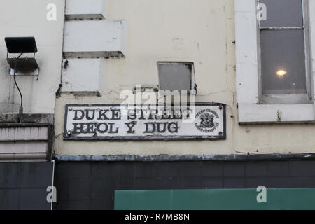 Duke Street name Anmelden Hauptstadt schwarze Buchstaben auf weißem Hintergrund weiße und graue Wand voller Schmutz in Cardiff, Großbritannien geschrieben Stockfoto