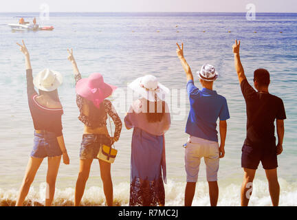 Silhouetten und Gruppe von fünf glücklichen asiatischen Menschen, die auf dem Hintergrund der leeren Sunset Beach. Reisen und meer ferien Konzept und Familie radeln Stockfoto