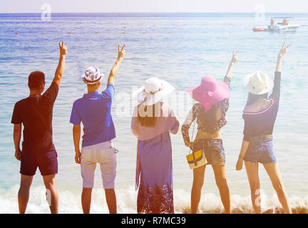 Silhouetten und Gruppe von fünf glücklichen asiatischen Menschen, die auf dem Hintergrund der leeren Sunset Beach. Reisen und meer ferien Konzept und Familie radeln Stockfoto