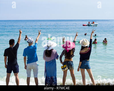 Silhouetten und Gruppe von fünf glücklichen asiatischen Menschen, die auf dem Hintergrund der leeren Sunset Beach. Reisen und meer ferien Konzept und Familie radeln Stockfoto