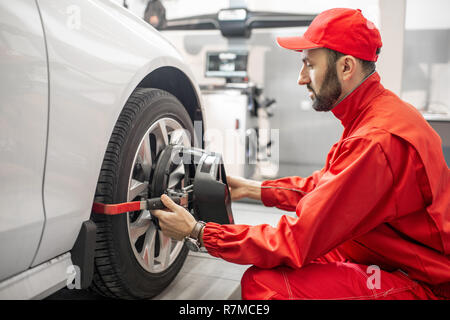 Stattliche Automechaniker in Rot einheitliche Festsetzung Festplatte für Spur am Auto Service Stockfoto