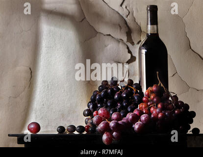 Hier ist Wein und Weintrauben mit Sonnenlicht durch ein Fenster beleuchtet. Dies ist eine Fotografie. Stockfoto