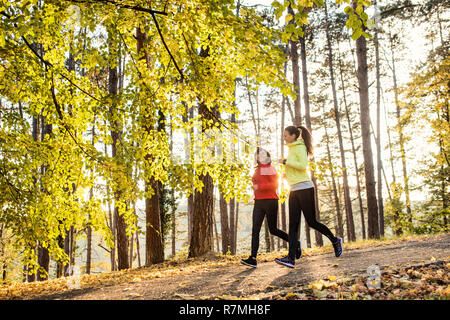 Zwei weibliche Läufer joggen draußen in Wald im Herbst Natur. Stockfoto