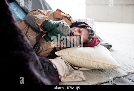 Obdachlose Bettler Mann auf dem Boden liegen im Freien in Stadt, Aufwärmphase Hände. Stockfoto