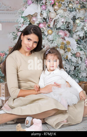 Glückliche Mutter und ihre kleine Tochter zu Weihnachten mit Tannenbaum und Geschenke eingerichtet Stockfoto