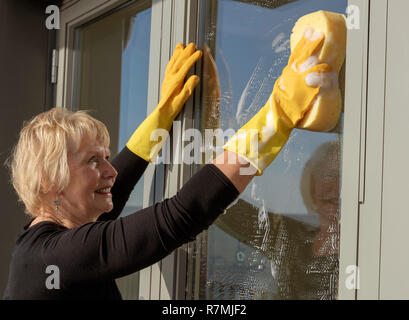 Frau Reinigung der Außenseite der Fenster mit einem Schwamm und Seifenlauge. Stockfoto