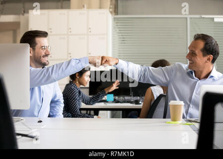 Freundlich lächelnden männlichen Kollegen Faust stoßen am Arbeitsplatz Stockfoto