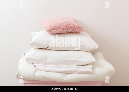 Ein Haufen von Sauber gebügelte Bettwäsche und ein Handtuch liegt auf der Kommode. Stockfoto