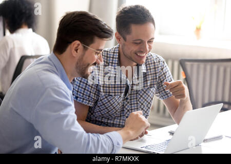 Die männlichen Kollegen mit Laptop, gemeinsam Spaß haben bei der Arbeit Stockfoto