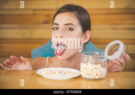 Marshmallow Paradies. Lustige Frau genießen essen Marshmallows. Pretty Woman halten Marshmallows auf ihrer Zunge. Candy Girl mit süßem Gebäck. Junk Food. Ungesunde und schädliche Lebensmittel. Süße Snack Stockfoto