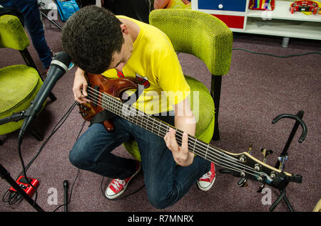 Sänger Bass Gitarristen sitzen sein Instrument testen Stockfoto