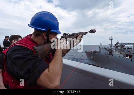 EAST CHINA SEA (20. März 2017) Die Gunner Mate Seemann Dylan McCurry, von Antioch, Illinois, feuert einen Schuß aus dem amphibious Transport dock Schiff USS Green Bay LPD (20) auf die militärische Sealift Command Dry Cargo und Munition ship USNS Richard E. Byrd (T-AKE 4) Während eine Auffüll-anforderung auf See. Green Bay, Teil der Bonhomme Richard Expeditionary Strike Group, mit 31 Marine Expeditionary Unit begonnen, ist auf einer Routinepatrouille in der Indo-Asia-pazifischen Region Partnerschaften zu verbessern und eine fertige Antwort für jede Art von Kontingenz. Stockfoto