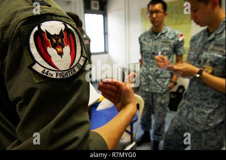 Ein US Air Force Pilot mit der 44Th Fighter Squadron von Kadena Air Base, Japan, und die Mitglieder der Republik Singapur Luftwaffe Mission Planung während der Übung bewältigen Tiger 2017 diskutieren in Korat Royal Thai Air Force Base, Thailand, 21. März 2017. Über 1.200 USA, Thai und Singapurischen militärische Mitglieder werden in CT 17 teilnehmen. Die jährliche multilaterale Übung ist die Verbesserung der gemeinsamen Bekämpfung der Bereitschaft und der Interoperabilität zwischen der Republik Singapur Air Force, Royal Thai Air Force, US Air Force, während gleichzeitig Stärkung der militärischen Beziehungen der drei Nationen". Stockfoto