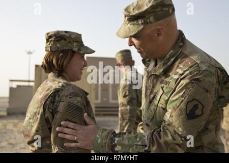 Brig. Gen. Alberto Rosende, Kommandierender General der 1. Mission unterstützt den Befehl, eine Armee finden Einheit aus Fort Buchanan, Puerto Rico, (rechts) schlägt den Garita Patch auf Zu 1 Lt. Mayra Hernandez, die 246Th Quartermaster Firma (leichenhalle Angelegenheiten) USCENTCOM theater Leichenhalle Affairs Office verantwortliche Offizier, während einer Zeremonie im Camp Arifjan patchen, Kuwait, am März 20, 2017. Stockfoto