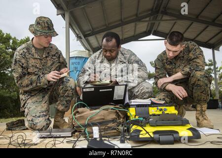 Us-Marines mit chemischen biologische, radiologische nuklearen (CBRN) Platoon, G-3, 1 Marine Flugzeugflügel (MAW), Marine Flügel Hauptsitz Squadron 1 und US Air Force Staff Sgt. Patrick Joyner, ein Assistent, der Incident Commander mit 18 Bauingenieur Squadron, 18 Flügel, Notizen während eines simulierten CBRN-antwort Bohren im Kampf Stadt, Okinawa, Japan, 21. März 2016 diskutiert. Notfallübungen ermöglichen CBRN-Platoon Fähigkeiten der Commander der Ausübung die Funktionsfähigkeit und Effizienz der Folgenbewältigung innerhalb der 1 MAW CBRN-response element Set zu verbessern. Stockfoto