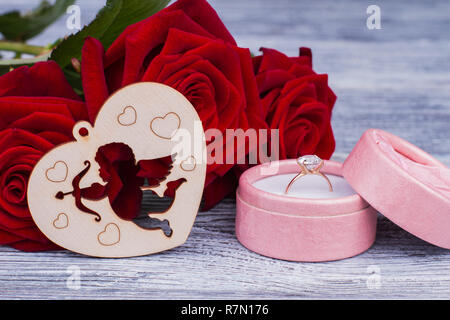 Romantische Hintergrund mit Rosen und goldenen Ring. Engagement Ring in der Box, rote Rosen und Herzen aus Holz. Happy Valentines Tag. Stockfoto