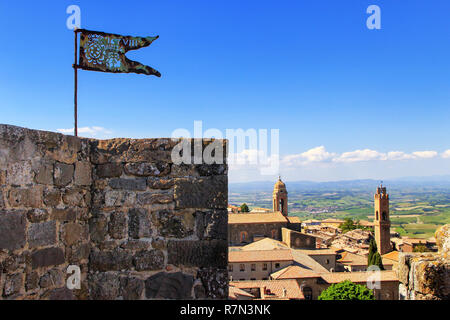 Metal Flagge auf der Oberseite von Montalcino Festung Turm im Val d'Orcia, Toskana, Italien. Die Festung wurde 1361 auf dem höchsten Punkt der Stadt erbaut. Stockfoto