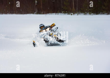 In snowdrift snowmobile Fahrer schnell in die Kurve fahren. Reiten mit Spaß im weißen Schnee Pulver während der backcountry Tour. Extreme Sport Abenteuer, Outdoor Aktivitäten Stockfoto