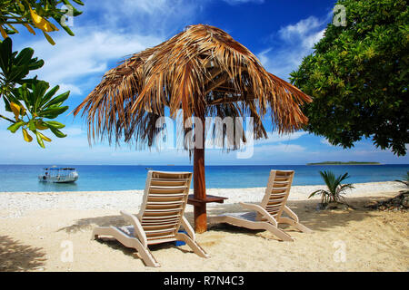 Liegestühle mit strohgedecktem Dach an einem weißen Sandstrand, South Sea Island, Mamanuca, Fidschi. Stockfoto