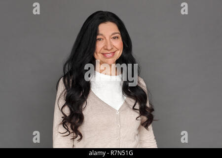 Freestyle. Reife Lady stehen isoliert auf Grau lächelt glücklich Stockfoto