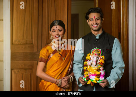 Happy maharashtrian Paar in traditioneller Kleidung feiern ganapati Festival mit einer kleinen Statue von Lord Ganesha. Stockfoto