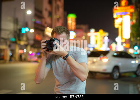 Junge touristische Mann fotografieren mit der Kamera in den Straßen von Chinatown bei nacht Stockfoto